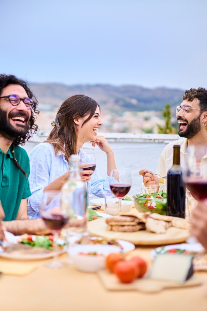Millennial happy people laughing sitting at food table with red wine enjoying sunny time on rooftop - Wine tasting Barcelona | Play Tour Barcelona